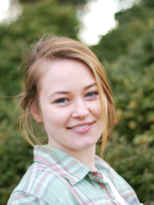 Smiling woman outdoors with blurred greenery background